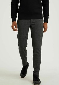 Grå rutiga byxor i vävt tyg, skräddarsydd passform, med en mjuk yta. Bärs med en svart sweatshirt och svarta skor.