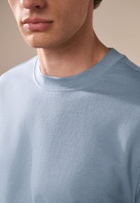 Lichtblauwe katoenen trui met een ronde hals, voorzien van een gladde stofstructuur en subtiele stiksel details.