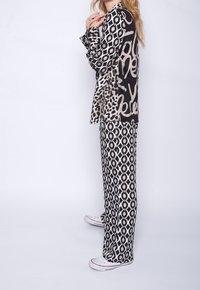 Black and white patterned lounge set featuring a long-sleeve top with mixed animal print and geometric designs, paired with wide-leg pants.
