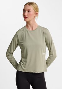 Hellgrünes, langärmliges Sportoberteil mit rundem Ausschnitt und gerippter Textur. Verfügt über ein kleines Logo auf der Vorderseite und enganliegende Ärmel.