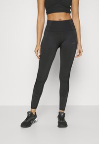 Black athletic leggings with a high waist, featuring textured striped accents on the sides and a fitted design. Pairing with black athletic shoes.