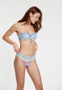 Bikini set so zaujímavým cikcakovým vzorom v mnohých farebných odtieňoch. Vrchná časť má bandeau strih s viazaním a spodná časť je klasického strihu.