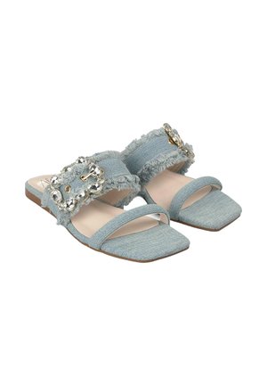 Blue denim slide sandals with frayed edges, square toes, and a large jeweled buckle as a prominent detail. Soft fabric and flat sole.