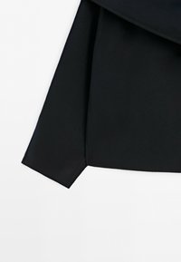Black fabric sleeve with a folded cuff, slightly angled on a white background.