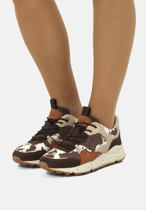 Sneaker marroni e beige con design a fantasia bovina, caratterizzati da una tomaia testurizzata, chiusura con lacci e suola maculata per un ulteriore contrasto.