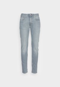 Jeans de mezclilla azul claro con un ajuste Slim, que cuentan con cinco bolsillos, una bragueta con botones y detalles de costura sutiles en los bolsillos traseros.