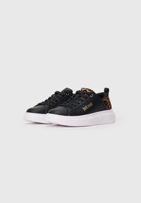Adidași negri cu talpă albă, cu accente de imprimeu leopard pe călcâi și limbă, șireturi negre și text auriu "Just Cavalli" pe lateral.