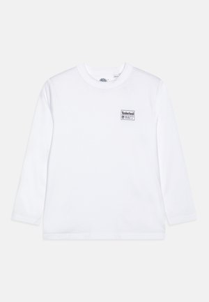 Witte longsleeve T-shirt van katoen, met een zwart Timberland logo patch op de linkerkant van de borst. Rond de halslijn, standaard pasvorm.