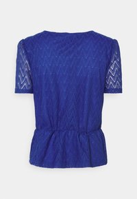 Haut bleu à manches courtes avec motif en dentelle en zigzag, taille légèrement froncée et manches semi-transparentes.