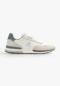 Sneaker beige chiaro con tomaia in tessuto liscio, dettagli in suede grigio, un tallone verde e una suola bianca con motivo a rombi. Logo a forma di teschio sul lato.