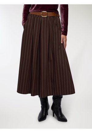Gonna a pieghe marrone con righe verticali bianche, dotata di tasche laterali e una cintura marrone con fibbia dorata. Indossata con stivali neri al ginocchio.