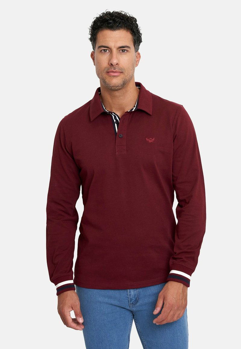 Camisa polo de manga larga burdeos con cuello puntiagudo, puños a rayas y un logo bordado en el pecho. Material de algodón, ajuste relajado.