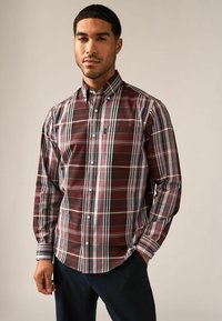 Camisa de botones de cuadros burdeos, con rayas blancas y azules. Mangas largas, puños abotonados y un bolsillo en el pecho. Tejido de mezcla de algodón.