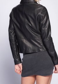 Zwarte leren jas met een aansluitend ontwerp, een gladde textuur en een platte kraag. Heeft naaddetails en een korte zoom.