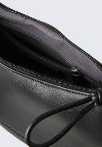 Schwarze Lederhandtasche mit Reißverschluss, mit grauem Innenfutter und einer kleinen Tasche. Mit einem Kordelzug-Detail zum Sichern des Inhalts.