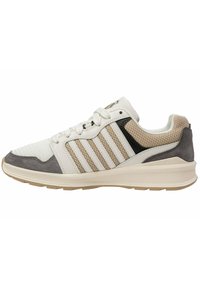 Zapatillas con una parte superior de malla blanca y sintética, acentos de ante en tono beige y gris, detalles negros y tres rayas blancas en el costado.