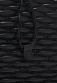 Borsa in pelle intrecciata nera caratterizzata da motivi testurizzati, una finitura liscia e una chiusura con coulisse con un accento ad anello.