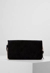 Borsa a mano in suede trapuntato nera con forma rettangolare, dotata di una tracolla in catena e leather. Texture liscia con un dettaglio di chiusura a pattina.