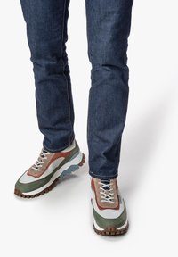 Tennarit, joissa on sekoitettua materiaalia vihreänä, ruskeana ja valkoisena, harmailla pohjilla ja karheilla kumipohjilla. Yhdistetty sinisiin farkkushortseihin.