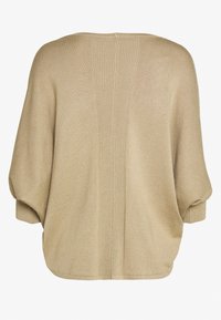 Beige oversize tröja med ribbad ryggdetalj, vida ärmar och en mjuk textur. Nertill är fållen bågformad och tyget verkar mjukt.