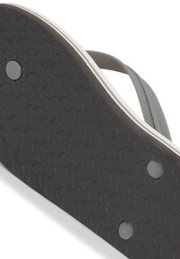 Sole in gomma nera per infradito con un motivo esagonale testurizzato, caratterizzata da una tracolla grigio scuro in contrasto e contrassegnata con "R" per il piede destro.
