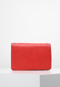 Borsa a tracolla rossa in pelle sintetica, di forma rettangolare, con fronte piatto, dettagli in argento e una texture liscia. Presenta una chiusura con patta ripiegata.