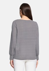 Zwart-wit geblokte blouse met lange mouwen, ronde halslijn en knoopmanchetten. De stof lijkt lichtgewicht met een zachte textuur.