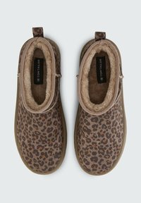 Scarpe slip-on marroni con design a stampa leopardata, interni in morbido pile e suola in gomma testurizzata. Presentano un pratico passante sul retro per indossarle facilmente.
