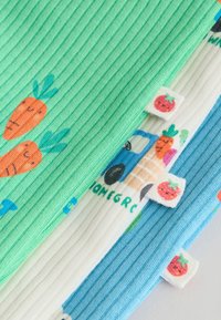 Tres mangas de tela acanalada en verde, blanco y azul con ilustraciones divertidas de zanahorias y fresas y etiquetas cosidas de fresa.