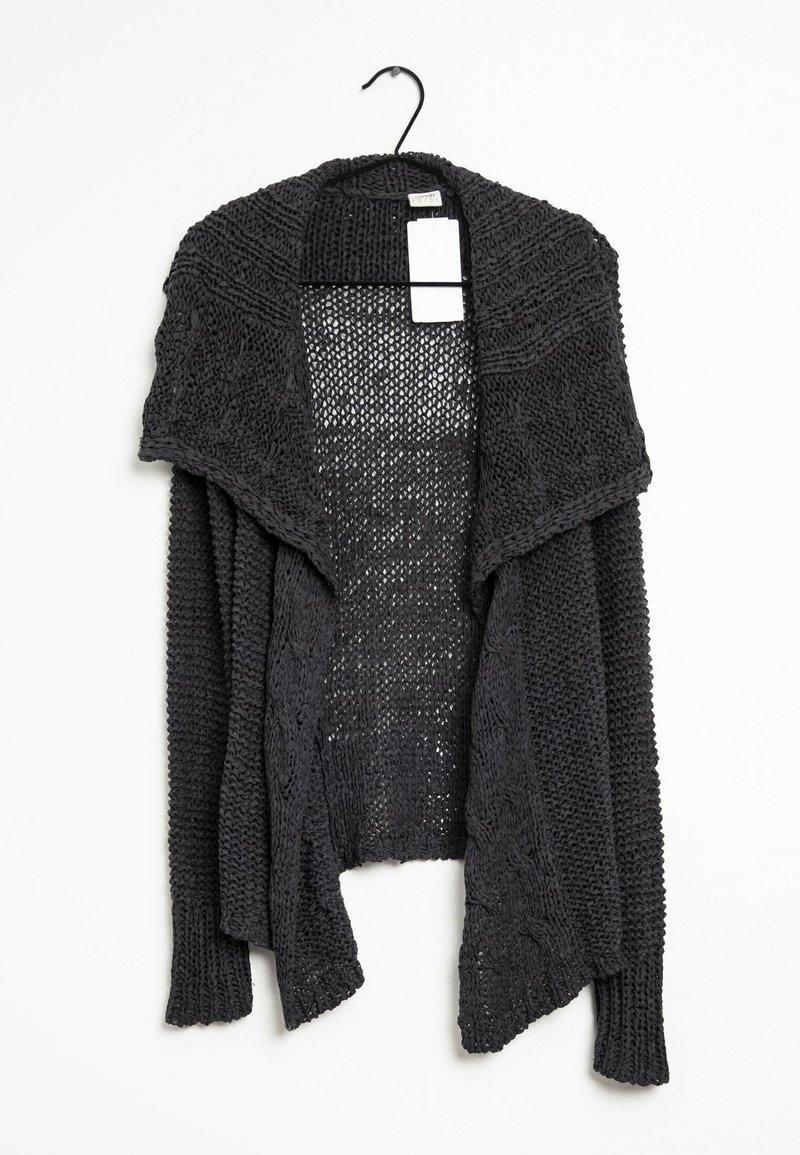 Cardigan noir en tricot avec une ouverture sur le devant, doté d'un large col et de motifs texturés. Suspendu à un cintre noir avec une étiquette.