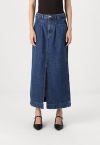 Denim maxi skirt in dark blue. Features a front slit, two side pockets, and a standard waistband with a button closure. Smooth texture.