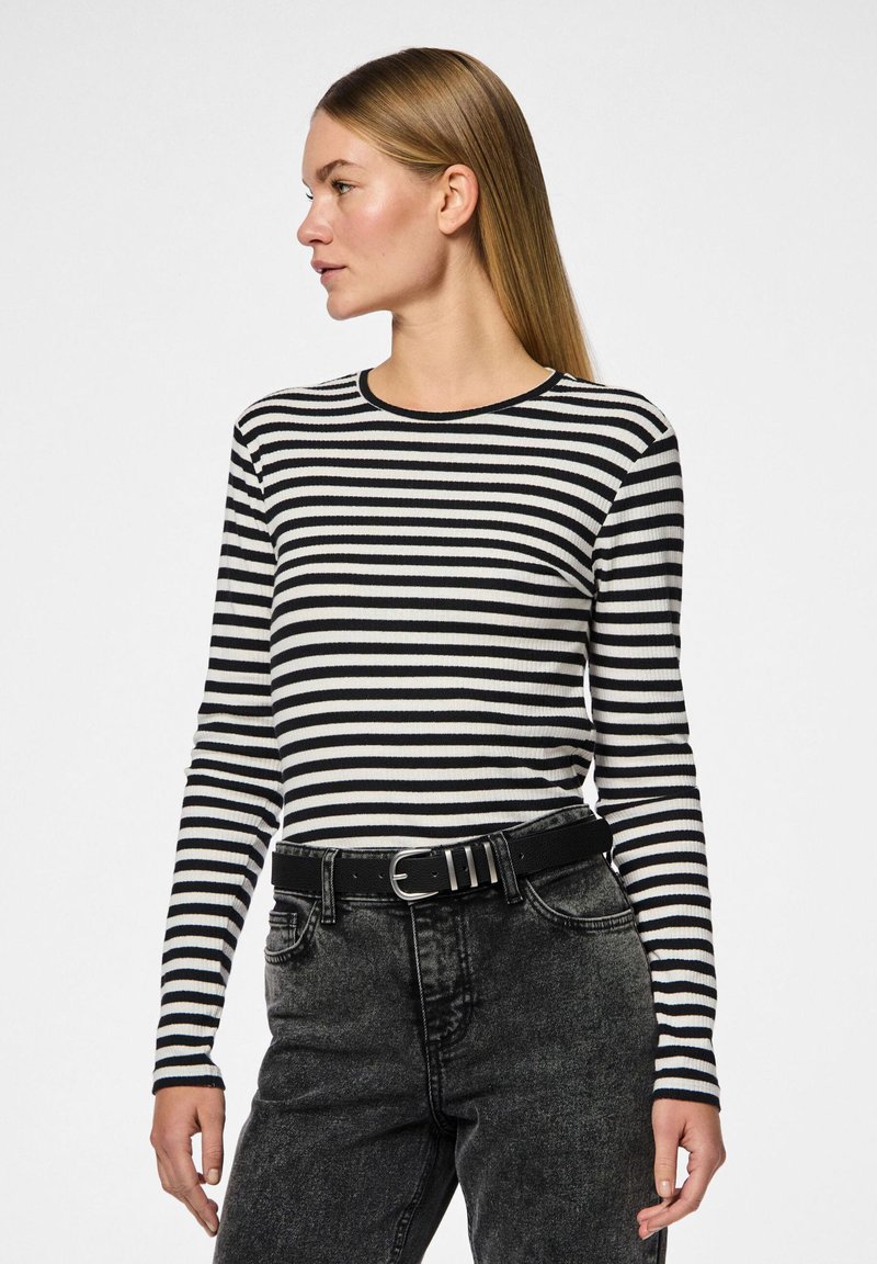Camisa de mangas compridas com riscas pretas e brancas, com textura canelada e decote redondo, combinada com jeans pretos de cintura alta e um cinto.