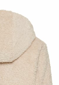 Beige Fleecejacke mit einer großen, weichen Kapuze, die aus strukturiertem Stoff gefertigt ist und ein lässiges Design aufweist. Keine sichtbaren Verschlüsse oder Muster.