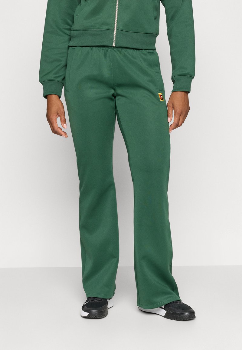 Pantaloni tuta verdi realizzati in un tessuto elasticizzato e solido. Presentano una vita elasticizzata e una piccola patch con logo sul lato frontale.