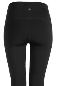 Zwarte leggings met een gladde textuur en hoge tailleband, voorzien van een klein logo detail aan de achterkant en platte naden voor comfort.