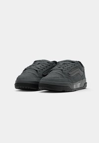 Le sneaker in suede nero presentano un colletto imbottito, dettagli perforati, lacci piatti e una suola in gomma testurizzata con un leggero tacco.