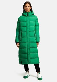 Manteau long matelassé vert avec capuche, présentant des poches zippées, une coupe droite et de subtils accents de logo ; fabriqué à partir d'un tissu isolant.