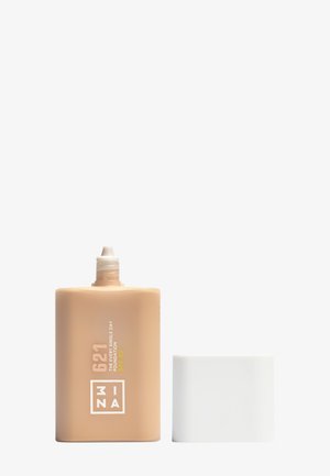 Beige foundationfles met witte dop, met een platte rechthoekige vorm, matte afwerking en bedrukte tekst die de tint en SPF aangeeft.