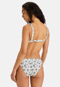 Dámske bikiny s kvetinovým vzorom v pastelových farbách, s nastaviteľnými ramienkami, zapínaním na chrbte a spodným dielom viazaným na boku. Vyrobené z ľahkej tkaniny.