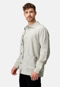 Giacca button-up grigia chiara realizzata in tessuto testurizzato, con colletto a bavero, due tasche frontali e chiusura con bottoni.
