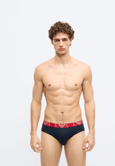 Cueca de algodão para homem em azul-marinho com cintura elástica vermelha com detalhe de logótipo. Textura suave, design ajustado e corte tipo cueca.