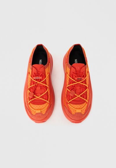 Ζεύγος φωτεινών πορτοκαλί και κόκκινων αθλητικών παπουτσιών με ύφασμα από δίχτυ και ελαστικές κορδόνια κλεισίματος σε λευκό φόντο.