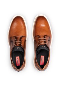 Scarpe in pelle marrone con una superficie liscia, punta rotonda, lacci neri e suole bianche a contrasto; presenta un'etichetta rossa all'interno.