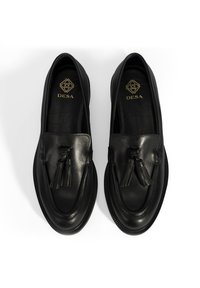 Schwarze Lederloafers mit glatter Oberfläche, dekorativen Quasten an der Vorderseite und einer strukturierten Gummisohle. Logo in Gold auf der Innensohle aufgedruckt.