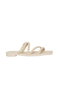 Sandali beige con tre strap testurizzati e borchiati. Design piatto con una suola minimalista e piccoli dettagli in gomma lungo il bordo.