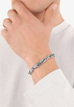 Braccialetto in catena d'argento con un centro rettangolare caratterizzato da un design marmorizzato bianco e nero, indossato su un polso.