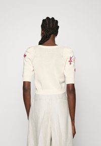 Cremefarbener, kurzärmeliger Strickpullover mit Puffärmeln, verziert mit bunten Blumenstickereien auf den Schultern und einem gerippten Saum für die Form.