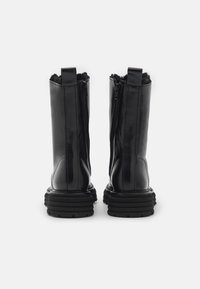 Bottines noires en cuir avec une finition lisse, dotées d'une fermeture éclair latérale, d'un col rembourré et de semelles épaisses en caoutchouc noir texturé.