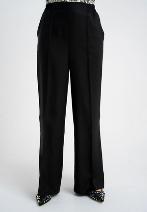 Czarne, szerokie spodnie z wysokim stanem noszone z czarno-białymi butami w groszki o szpiczastym nosku.