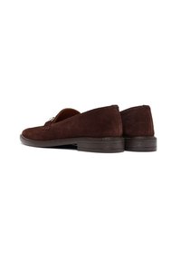 Un paio di mocassini in suede marrone scuro con tacco basso e impilato, dettaglio in metallo argentato sulla parte superiore, mostrati da angoli posteriori e laterali.